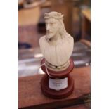An early 20th Century Iivory bust figure of Christ mounted upon an amber coloured phenolic socle,