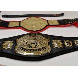 Two wrestling belts, one reading the World Heavyweight Wrestling Champion with brass plates,