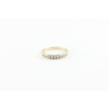 A 9ct yellow gold and diamond ring, channel set row of eleven round cut diamonds, shank impressed "