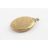 A 9ct. yellow gold oval locket, having engraved foliate scrolls to front, with pierced scroll mount,