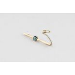 A yellow metal and blue stone bar brooch, having emerald cut blue stone to centre, (yellow metal