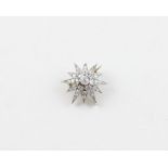 A white metal and diamond star brooch, of gently domed form, set old round cut diamond to centre,