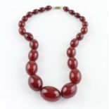 A string of graduated cherry amber beads, of ovoid form, the largest to centre length 30mm x