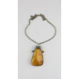 A large natural butterscotch amber pendant, within in white metal scroll top mount, height 75mm,