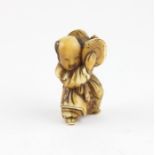 A Japanese Meiji netsuke holding a drum on his shoulder