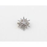 A white metal and diamond star brooch, of gently domed form set round brilliant cut diamond to