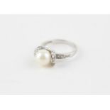 An 18ct. white gold, pearl and diamond dress ring, set large cultured pearl to centre in between