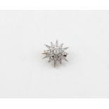 A white metal and diamond star brooch, of gently domed form, set old round cut diamond to centre