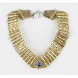 A yellow metal, enamel and ruby collar necklace, having central triangular pierced panel with