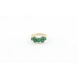 A 9ct. yellow gold and emerald ring, the centre four claw set round cut emerald flanked by