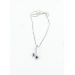 An 18ct. white gold, sapphire and diamond pendant, fashioned as a pair of entwined stems terminating