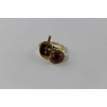 A yellow metal and garnet ring, having oval garnet in rub over setting with filigree work border,