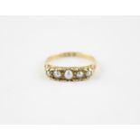 An 18ct. gold and graduated pearl ring, set five graduated pearls,the mount sides scroll engraved,