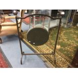 A dinner gong on a wrought iron stand.