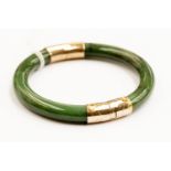 A jade and yellow metal hinged bangle, round section jade, the ends capped with yellow metal,