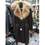 A brown leather full length long coat with a ginger fox fur collar, with a belt,