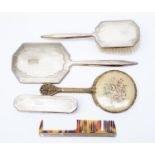 A four piece silver backed dressing table set of mirror brushes etc together with a petite point