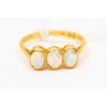 An opal ring, set with three oval rub-over set opals, set in 22ct gold, stamped, size O,