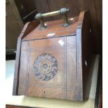 A wooden coal scuttle with carved design to the front and brass handle.