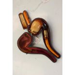 An amber and 9 ct gold cheroot holder and case, a Meerschaum pipe with amber mouthpiece,