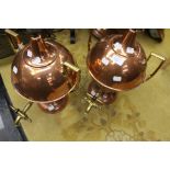 A pair of copper and brass spherical tea urns on a pedestal base with conical tops terminating in