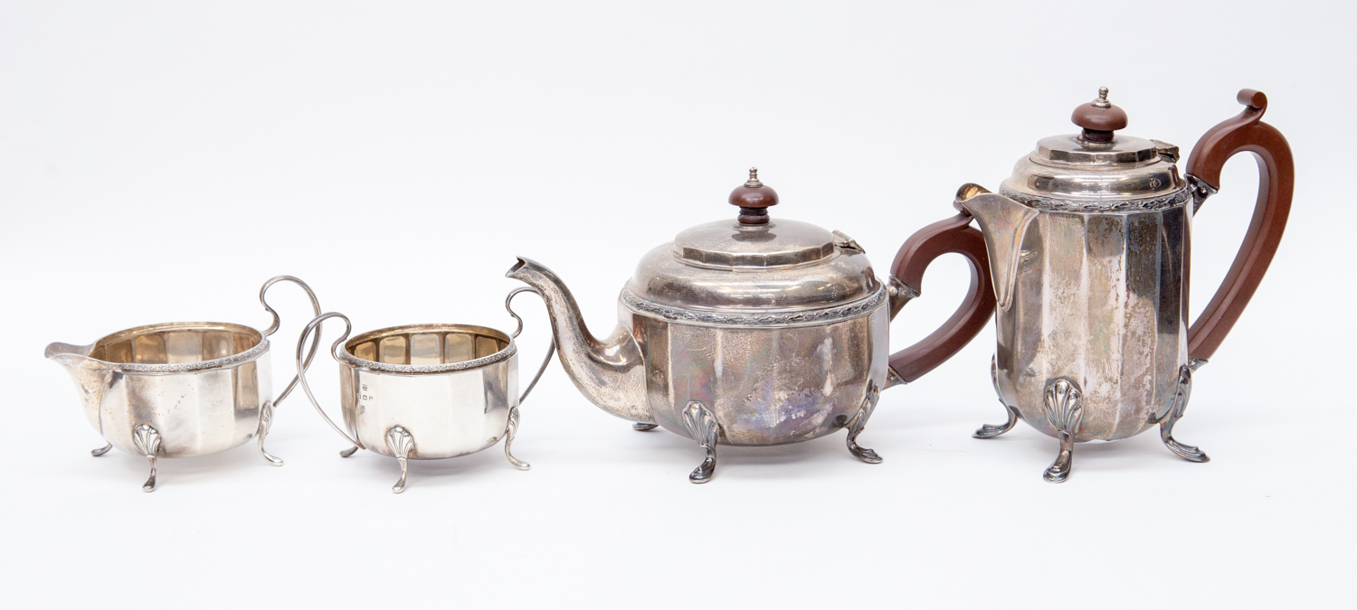 A George V silver four piece tea set, faceted form with laurel and berry rims, on four shell feet,