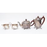 A George V silver four piece tea set, faceted form with laurel and berry rims, on four shell feet,