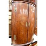 A Georgian bow fronted corner wall cabinet with double doors and three shelves inside