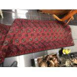 An early 20th Century red ground hand knotted woollen runner rug,