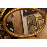 A late 19th Century giltwood overmantle mirror, oval form, fitted with bevelled edge glass,