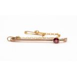 A Tourmaline and 9ct gold bar brooch, the round garnet rub-over set to the centre of the bar,