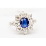 A sapphire and diamond cluster ring, the claw set central oval cut sapphire approx 0.
