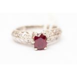 A ruby and diamond set dress ring, the oval claw set ruby approx 0.