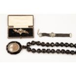 A collection of mourning jewellery to include jet type faceted beads with hair locket pendant,