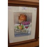 A contemporary still life watercolour depicting fruit on a table with a terracotta flagon,