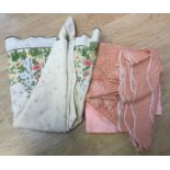Three round tablecloths, one peach (embossed) one cream with a floral print and a salmon pink,