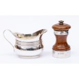 A silver cream jug and peppermill