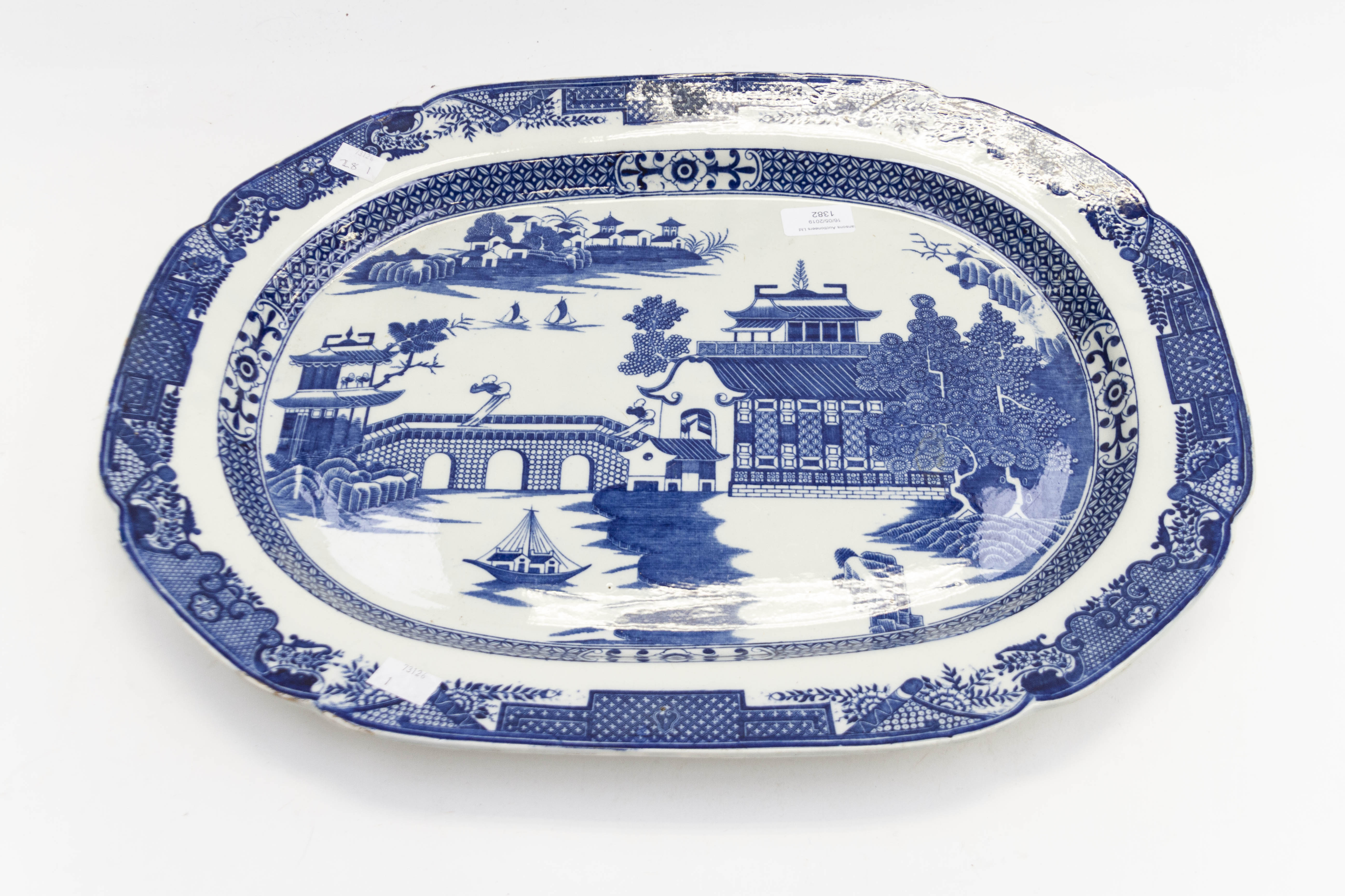 A large 19th Century Earthenware blue and white meat platter decorated with boats and pagoda within