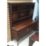 A George III oak dresser with rack, the base with four drawers and two doors between,