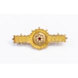 A Victorian 9ct gold brooch, seed pearl and red stone set centre with bead and rope decoration,