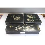 Three black papier mache painted boxes