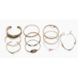 A collection of ten silver and white metal bangles including torques and hinged versions,