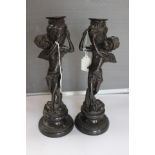 A pair of 19th Century bronze figural candlesticks, raised on circular socles,