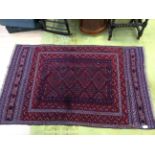 An Afghan hand knotted woollen rug, having a geometric design in navy blue and burgundy,