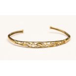 A diamond set 9ct gold torque bangle with open scroll work design by Brooks and Bentley,