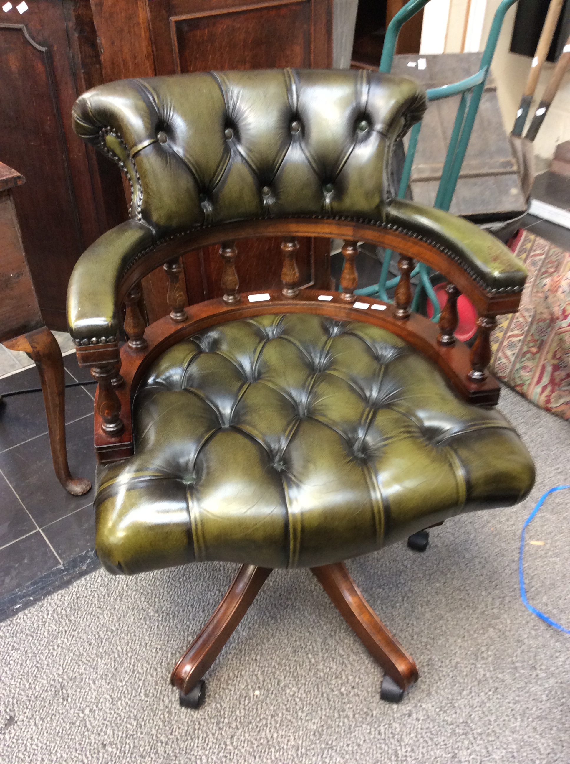 A traditional green leather upholstered deep buttoned swivelling captains chair