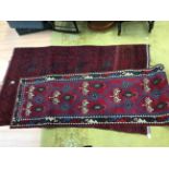 An early 20th Century red ground hand knotted woollen runner rug,