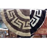Two circular fur rugs, of primative design, one in dark brown and cream,