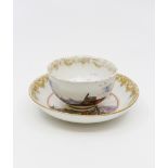A Meissen tea bowl and saucer, painted with sailing boats and merchants on the tea bowl,