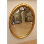 A late 19th Century giltwood overmantle mirror, oval form, fitted with bevelled edge glass,